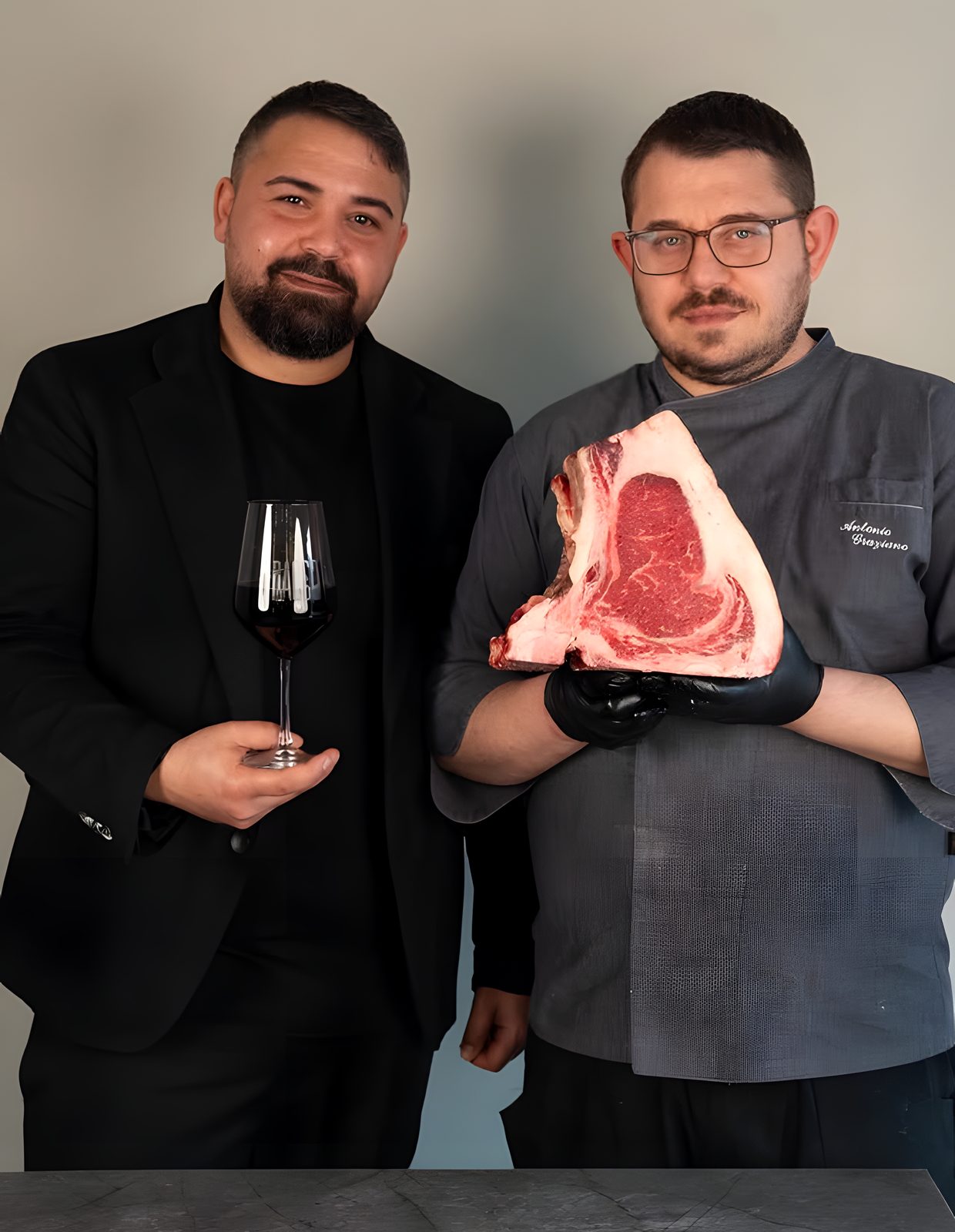 I due titolari di iBacco: uno con un calice di vino rosso, lo chef con una costata frollata